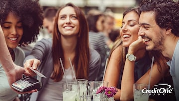 A woman with her friends at a restaurant paying for a meal with her credit card