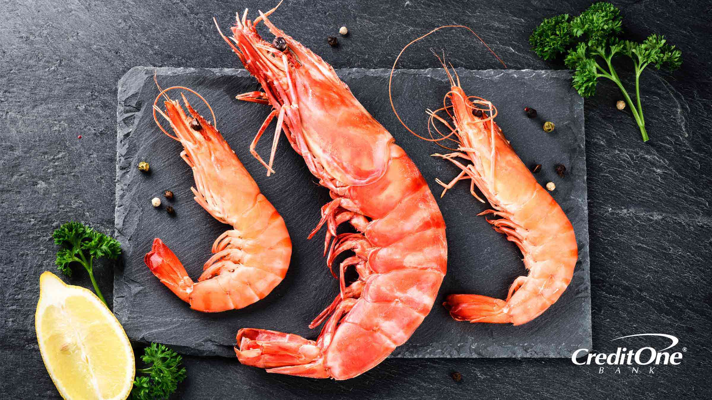 A jumbo shrimp and two regular shrimp on a slate plate