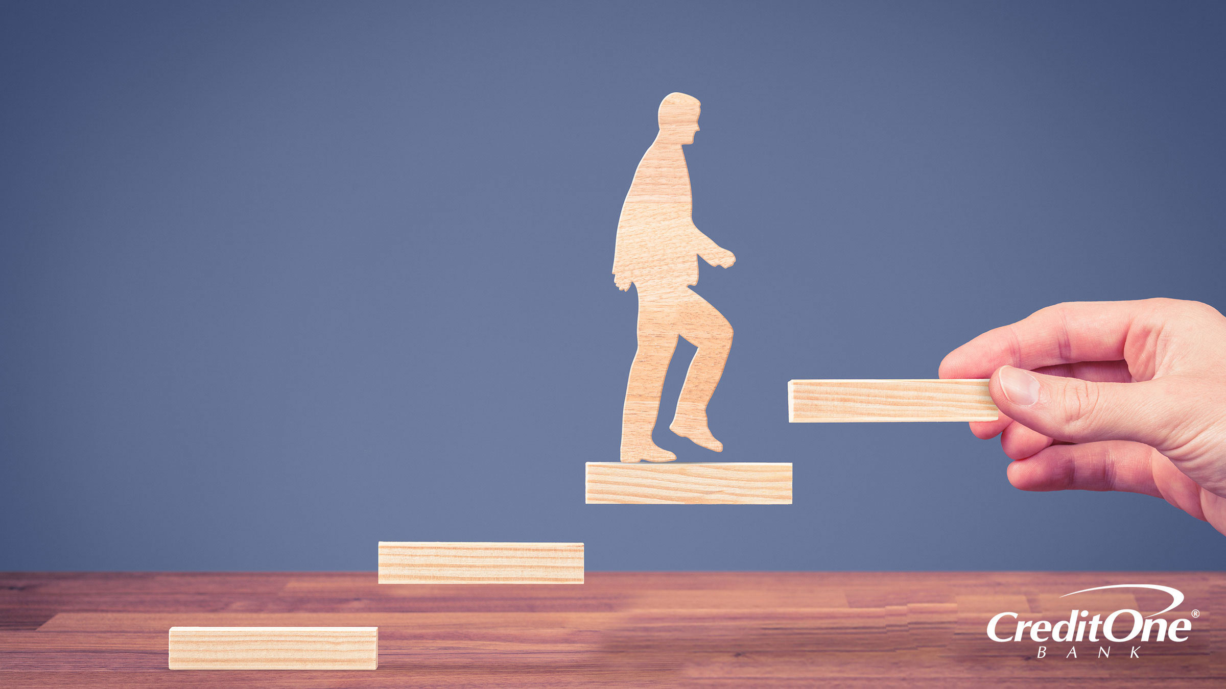 Demonstrating improved credit success by wooden block shaped like a man walking up a set of stairs
