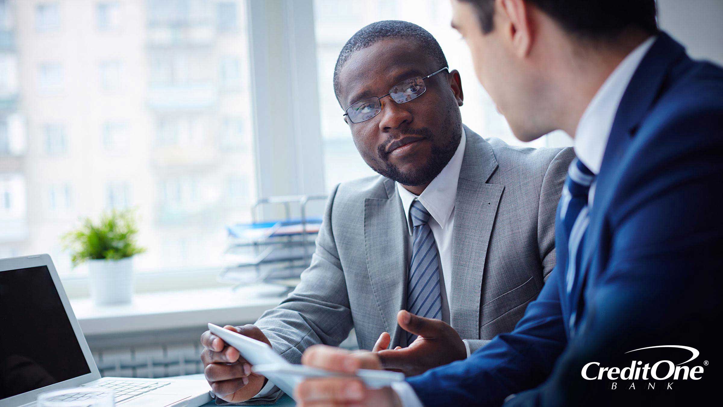 Two businessmen in office reviewing credit scores and other financial statements