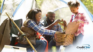 Family of three camping on summer vacation and picking grapes from basket