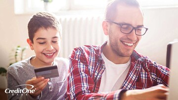 A boy holding a credit card and asking his father questions about credit