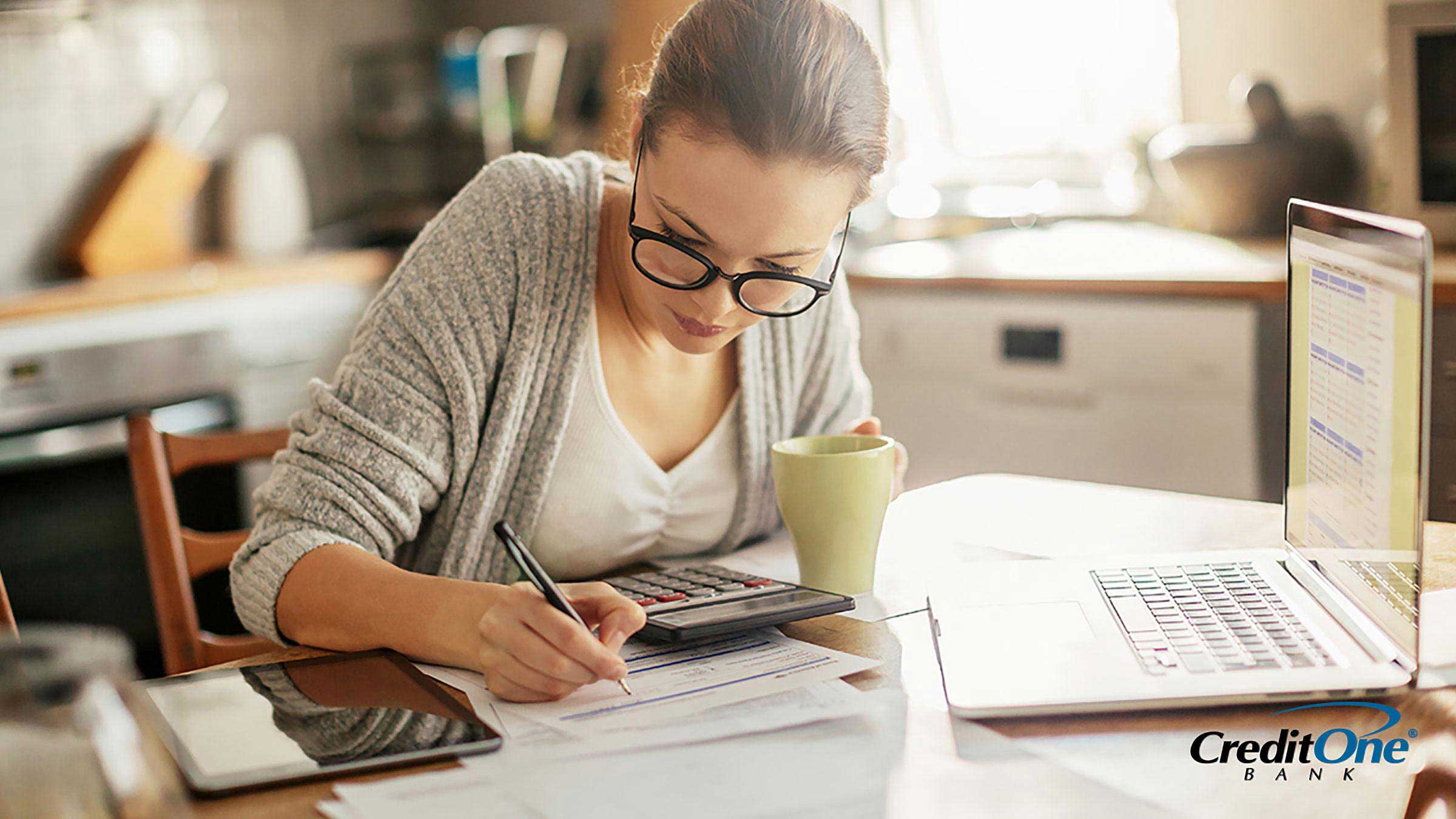 A woman sitting in her kitchen developing a plan to pay off her debt