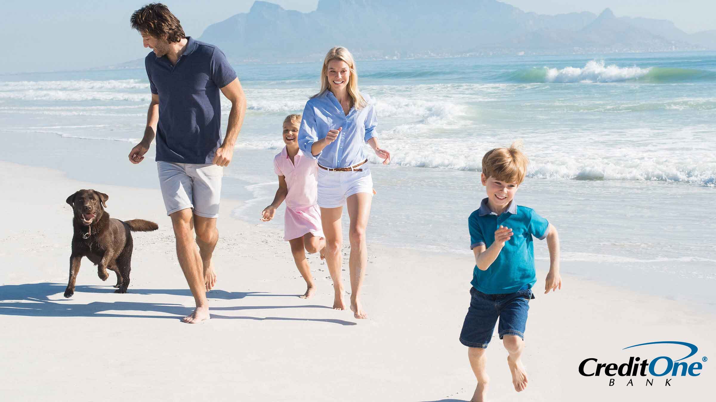 Family of four with a dog running on a beach during a family vacation