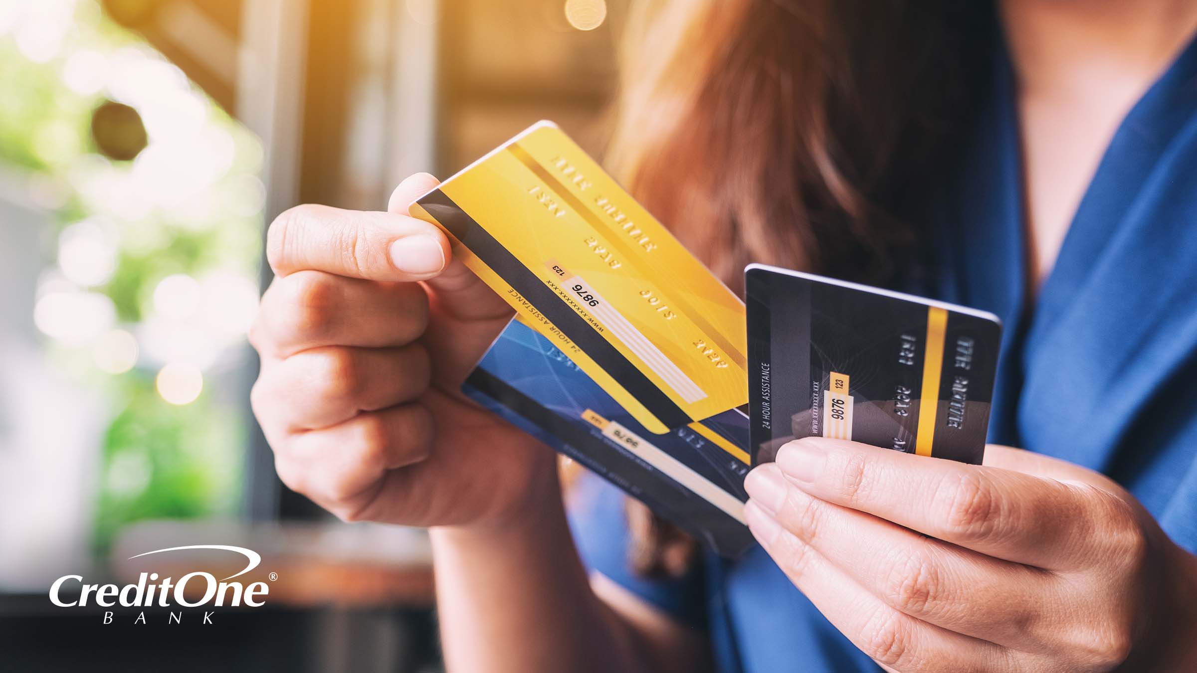 A woman holds a collection of credit and debit cards, trying to decide which to choose for her purchase.