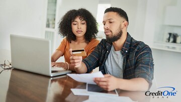 A young couple considers using their credit card to pay bills