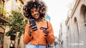 A young, Gen Z woman is using her credit card to make a payment on her phone.