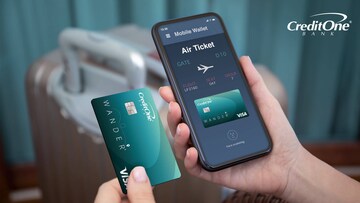 A woman’s hand holds a mobile phone showing plane tickets she bought with her travel rewards credit card