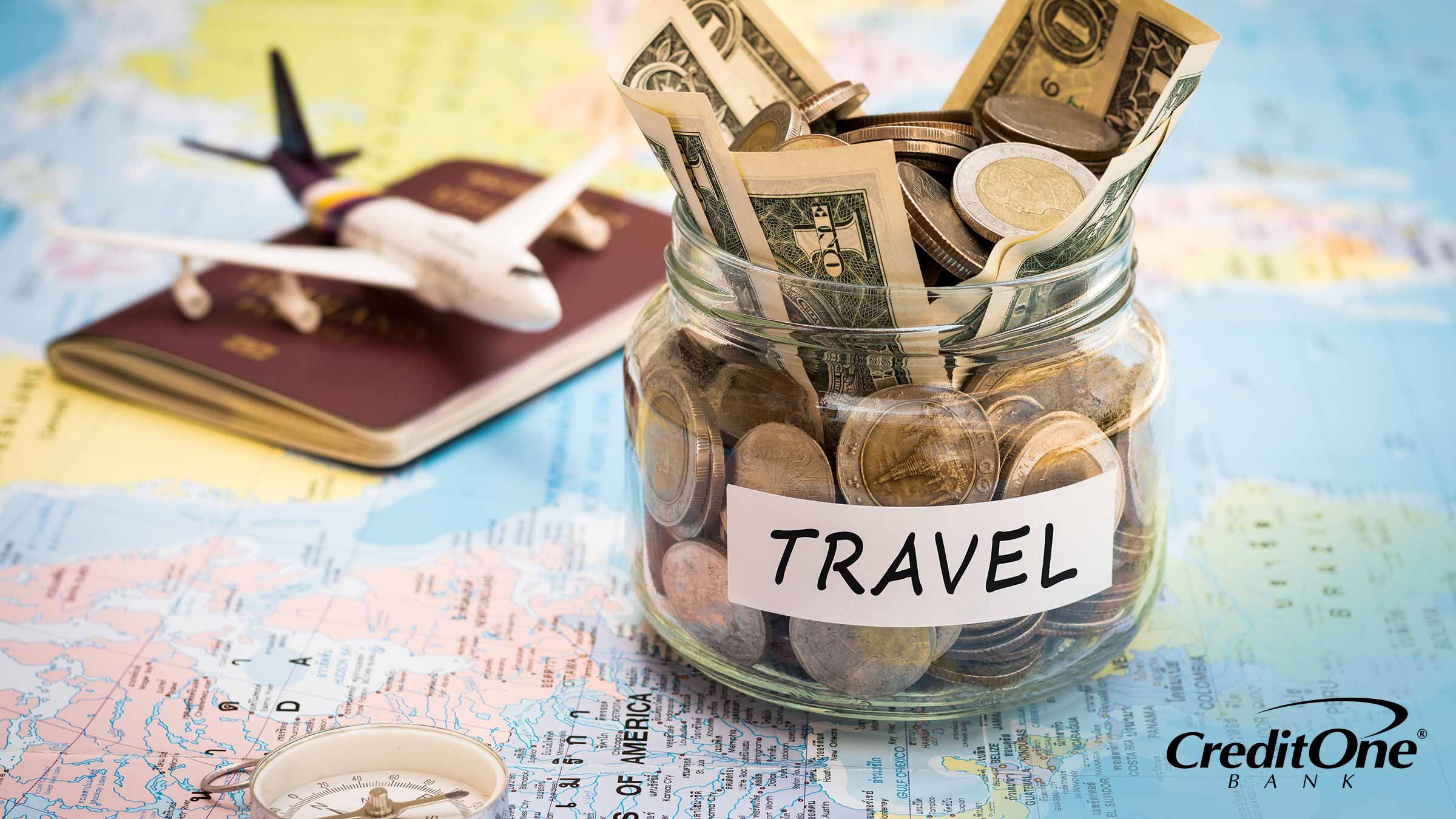 A vacation fund jar to save for annual travel sits on a map with passport and compass