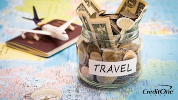 A vacation fund jar to save for annual travel sits on a map with passport and compass