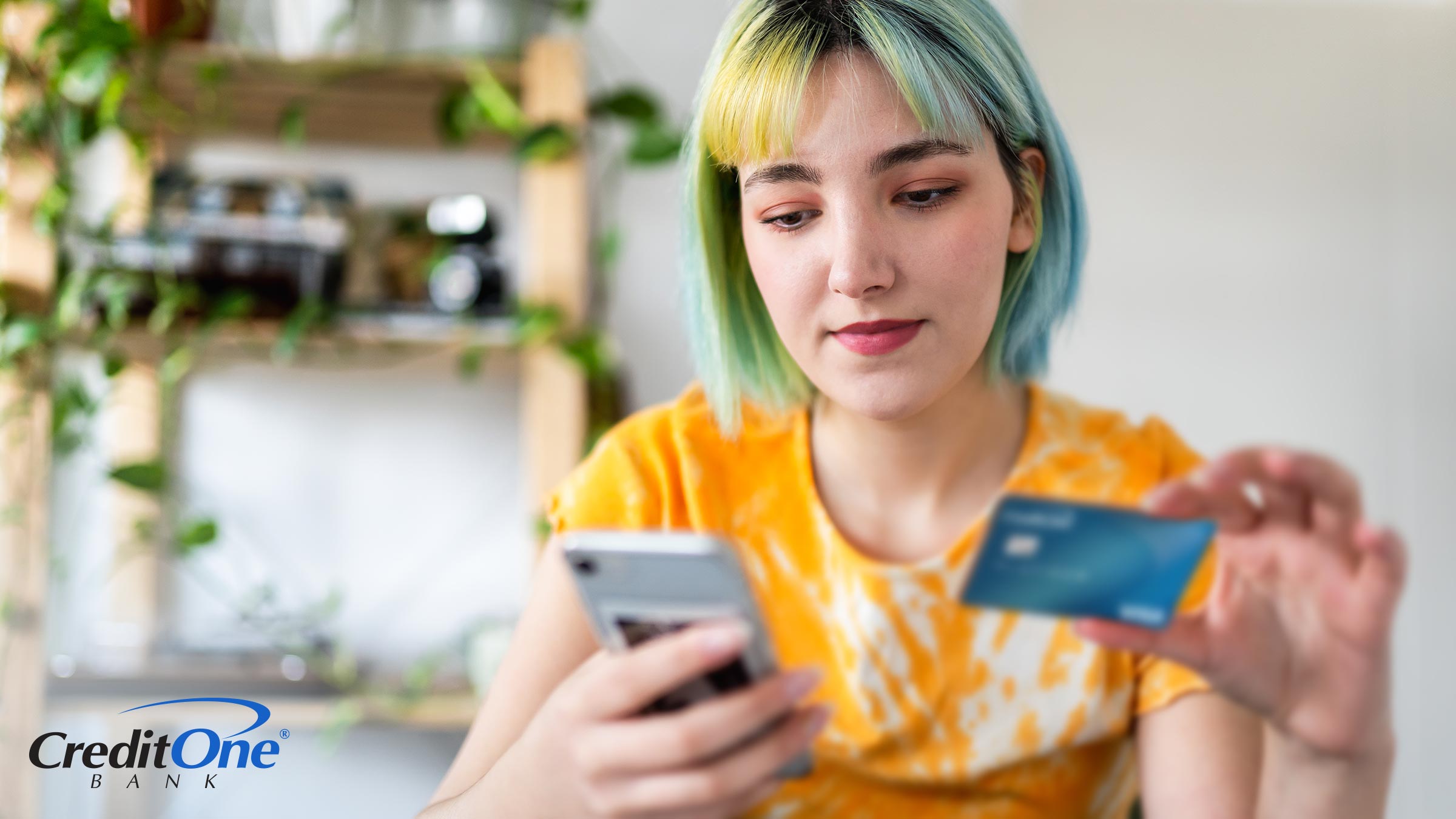 A young Gen Z woman with colored hair spends money online with her credit card and phone