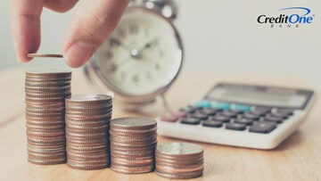 A hand stacks coins in step formation next to a clock and calculator, representing CD laddering