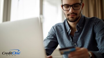 A man enters his credit card number into his computer to make a purchase online.