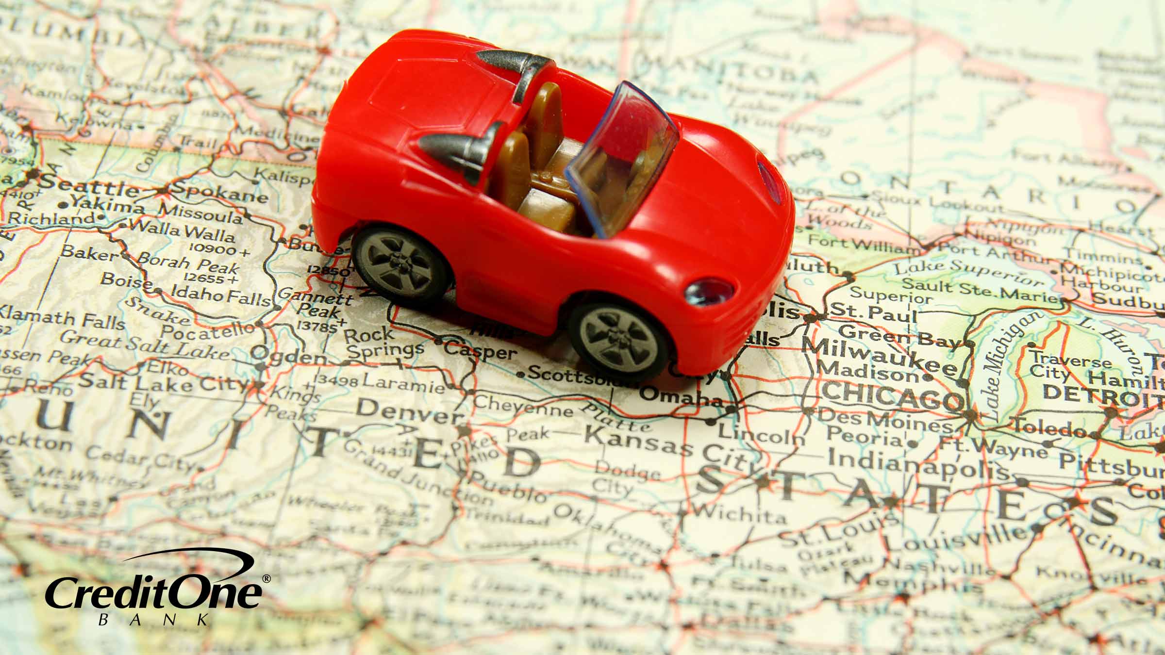 A red toy car rests on top of a United States map, signifying car insurance varying state by state.