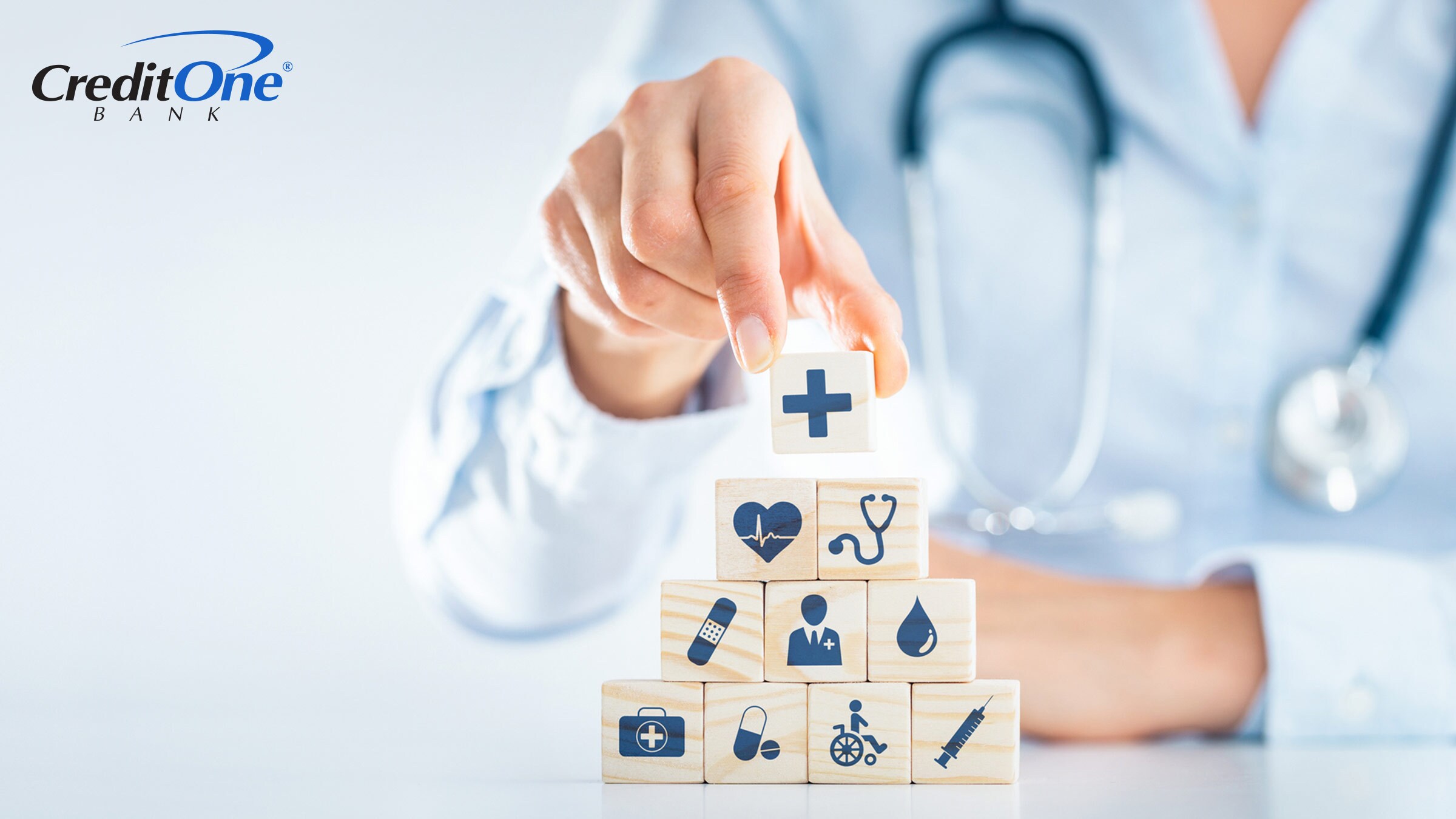 A doctor’s hand stacks blocks with health-related icons on them, representing cancer insurance.