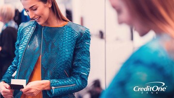 A woman checks the price tag while trying on a new jacket so she can keep up with trends without breaking the bank.