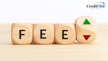 The word “fee” is spelled out on wooden cubes next to a cube with up and down arrows on it, signifying whether credit card annual fees are worth it or not.