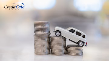 A toy car is climbing a stack of coins, representing auto insurance rates going up.