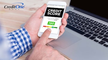 A man’s hands hold his smartphone, currently displaying his good credit score, which is a great way to receive multiple benefits.