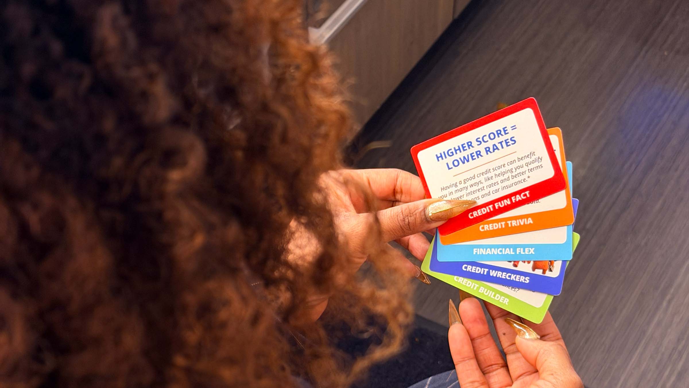 Woman holding the Credit One Bank Cards on the Table game.
