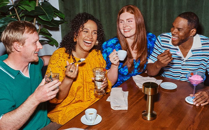 A group of four friends dining and laughing around a table