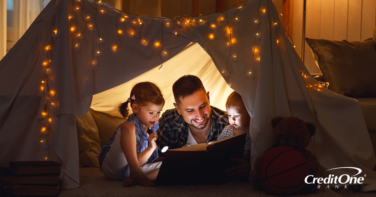 Father having fun by reading to his two kids while camping Father having fun by reading to his two kids while camping