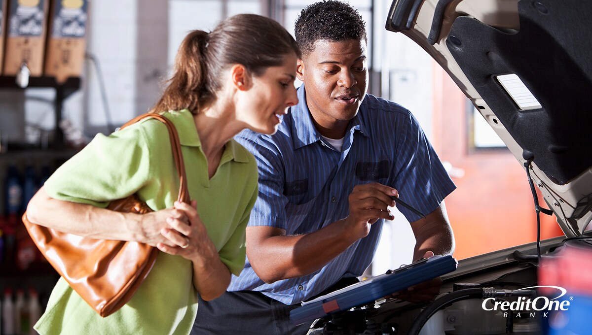 A woman reviewing car engine repairs with a mechanic A woman reviewing car engine repairs with a mechanic