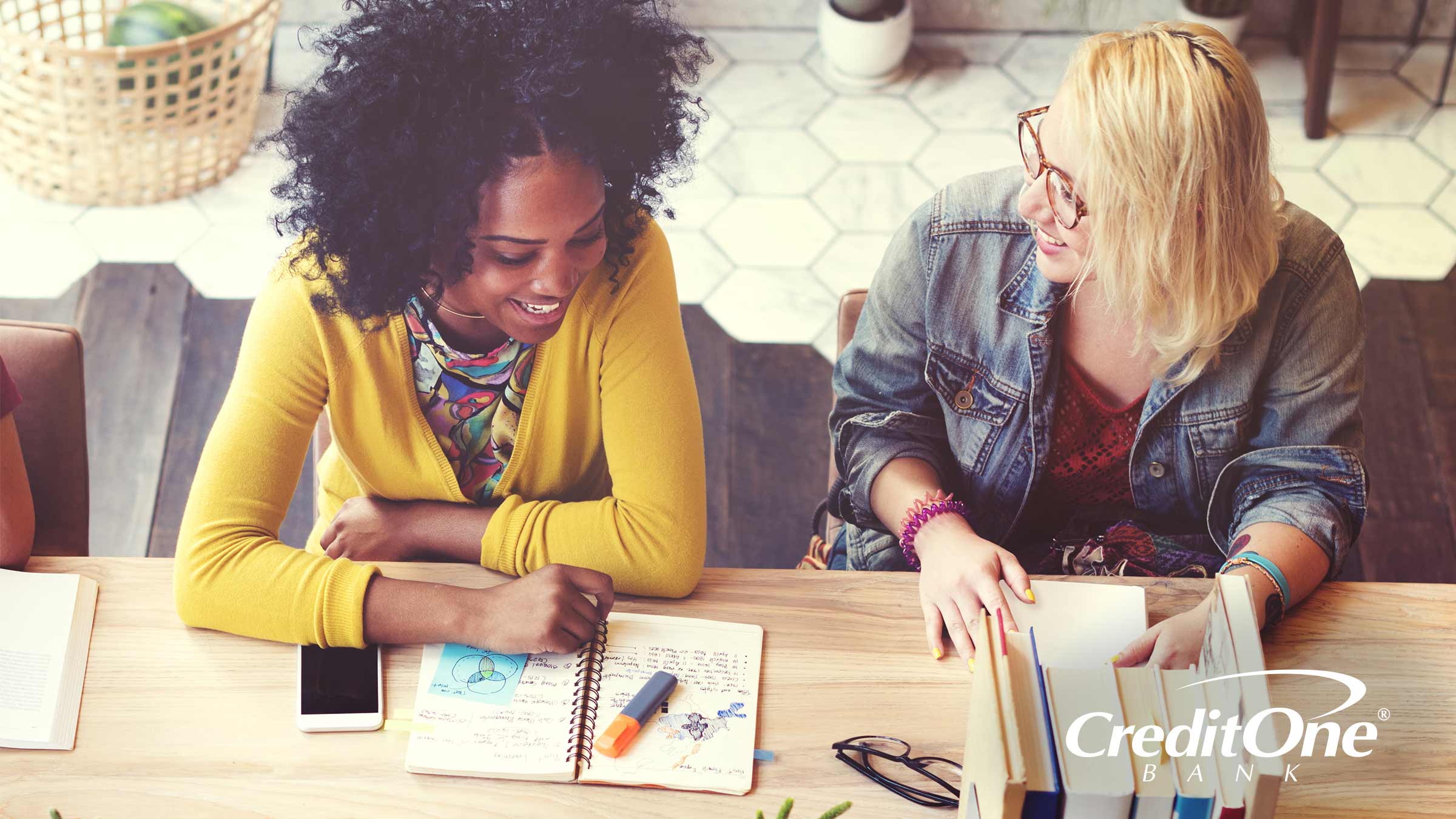 Two college students studying at a table discussing credit Two college students studying at a table discussing credit