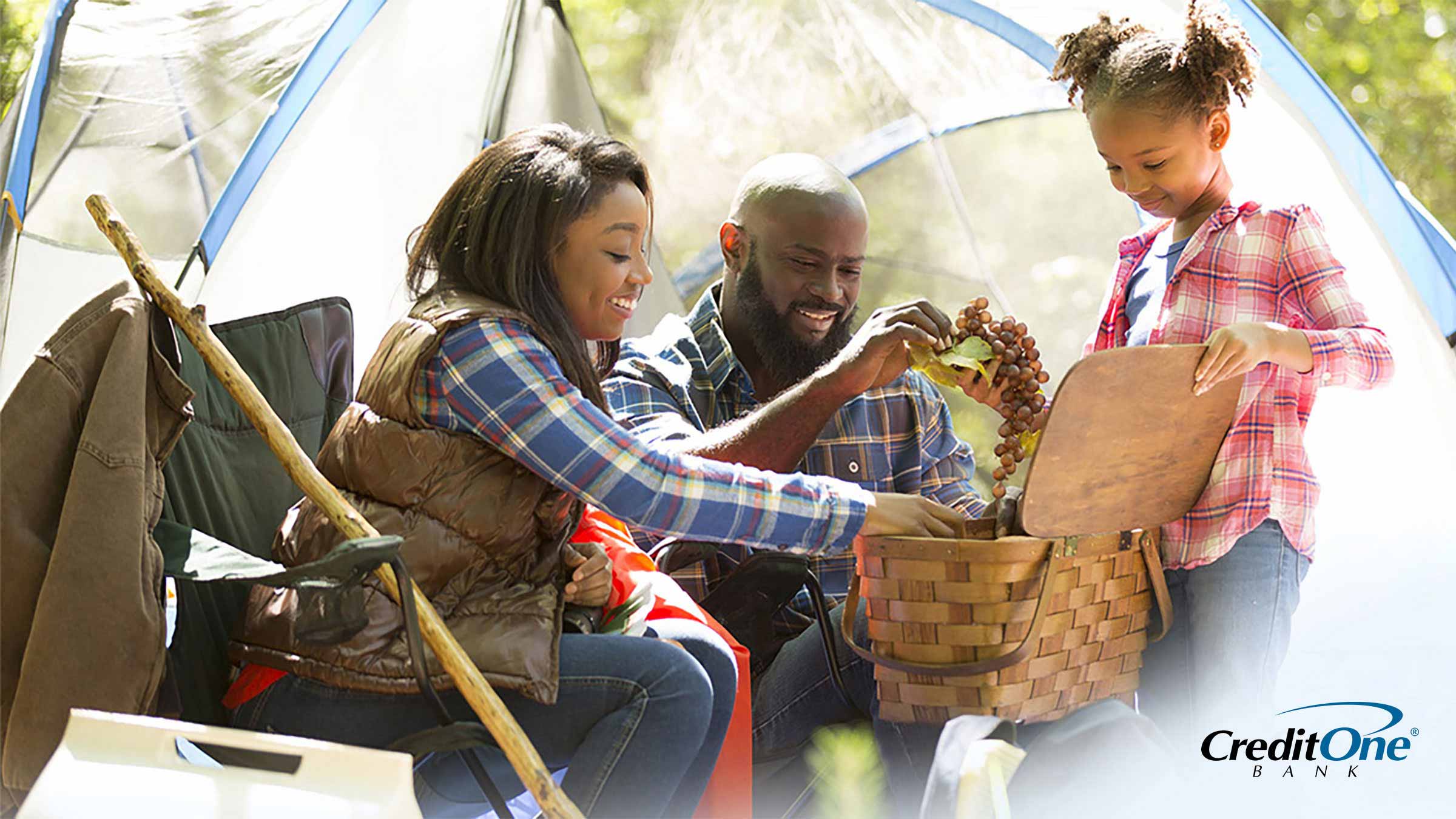 Family of three camping on summer vacation and picking grapes from basket Family of three camping on summer vacation and picking grapes from basket