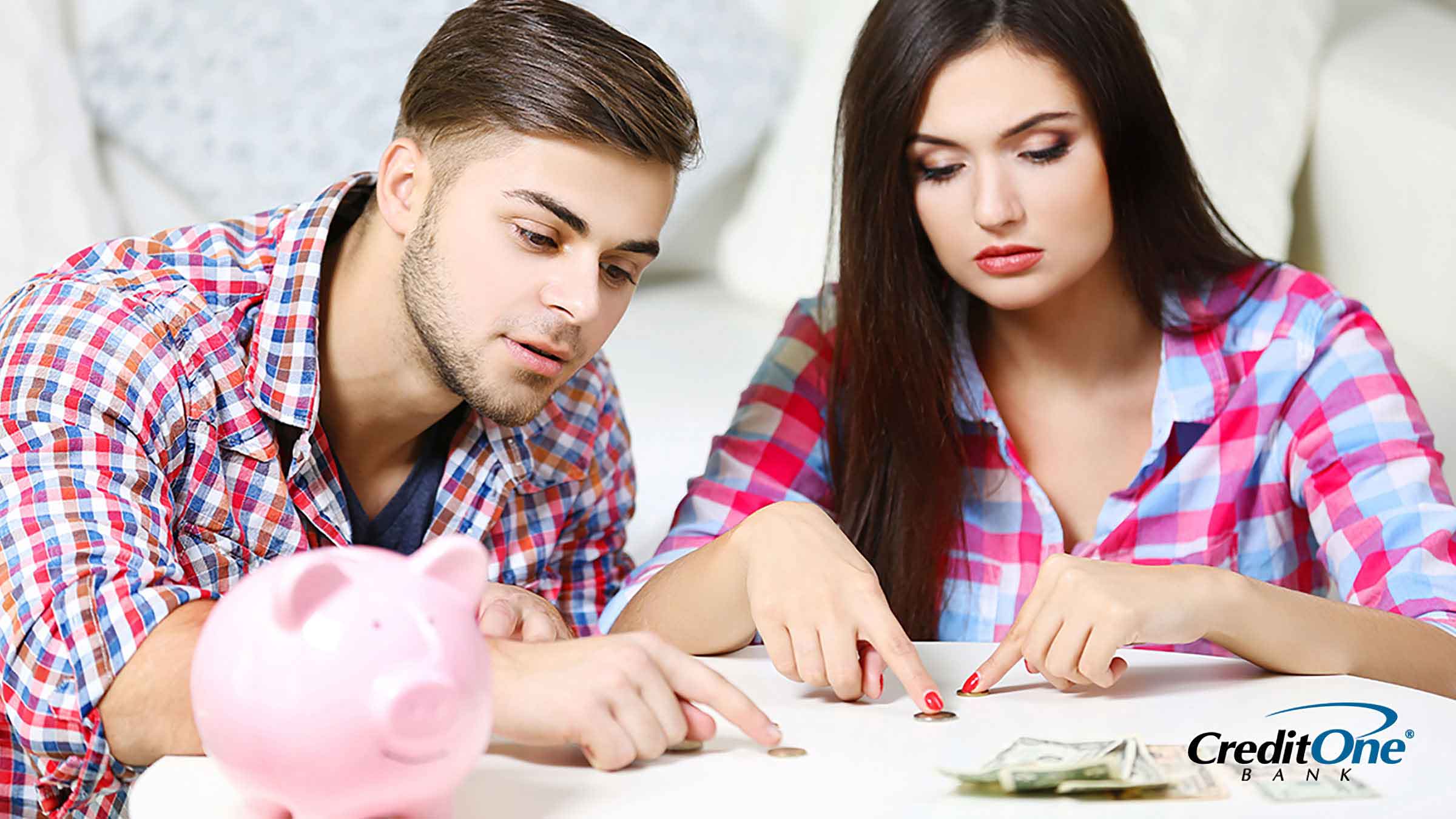 Young man and woman counting up their savings from a pink piggy bank
