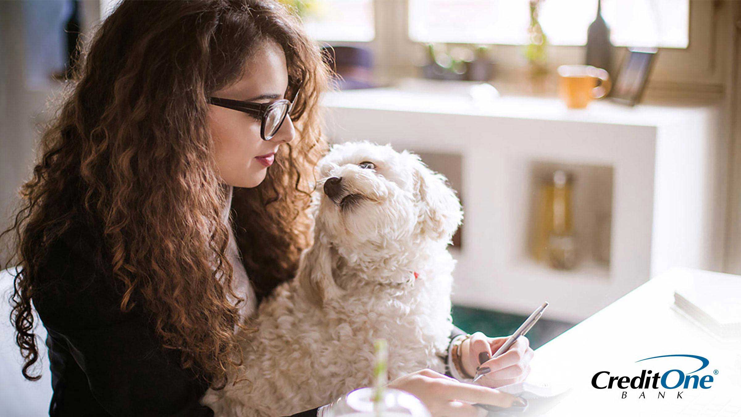 Woman with a dog in her lap calculating her finances on a computer