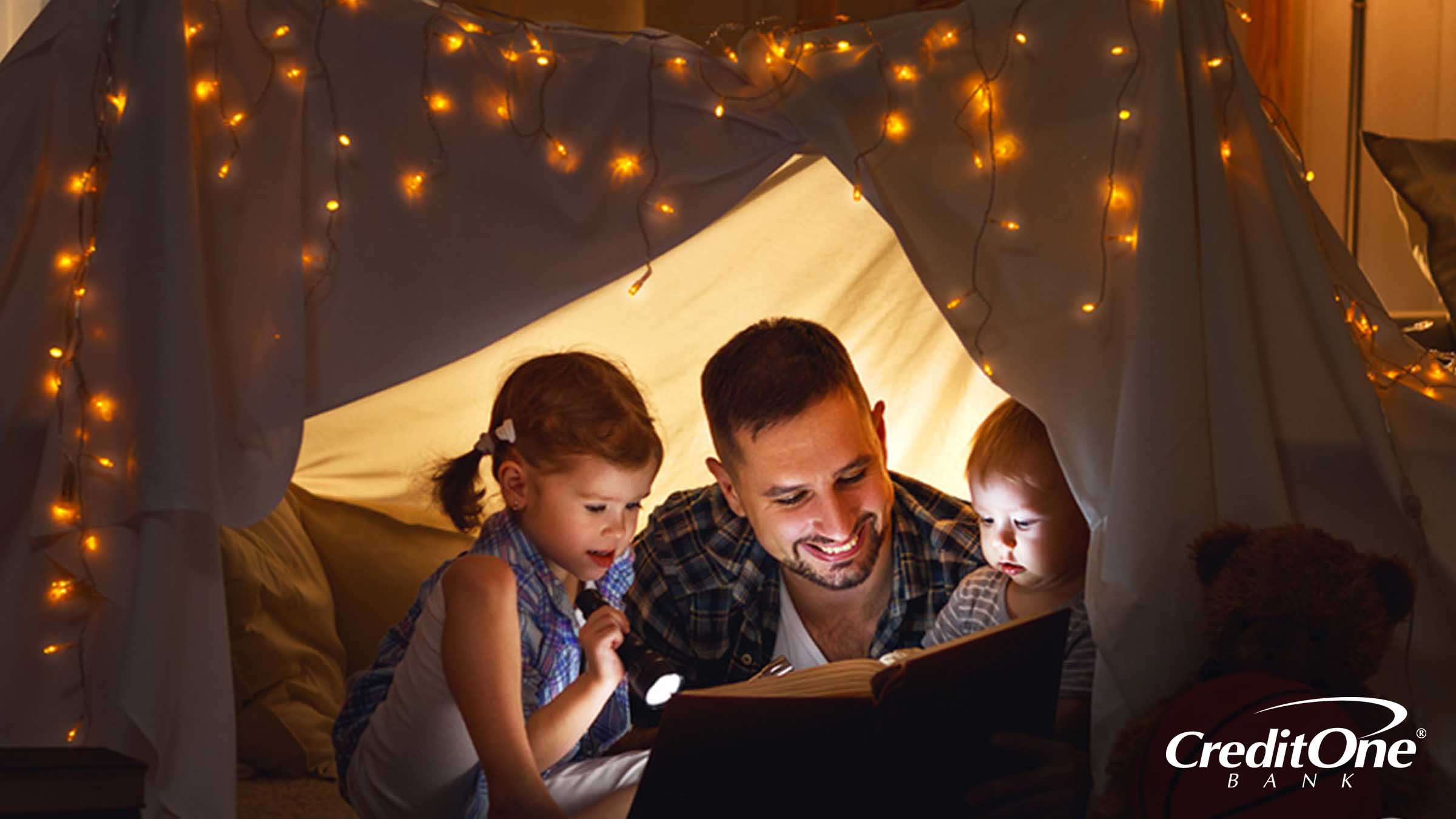 Father having fun by reading to his two kids while camping
