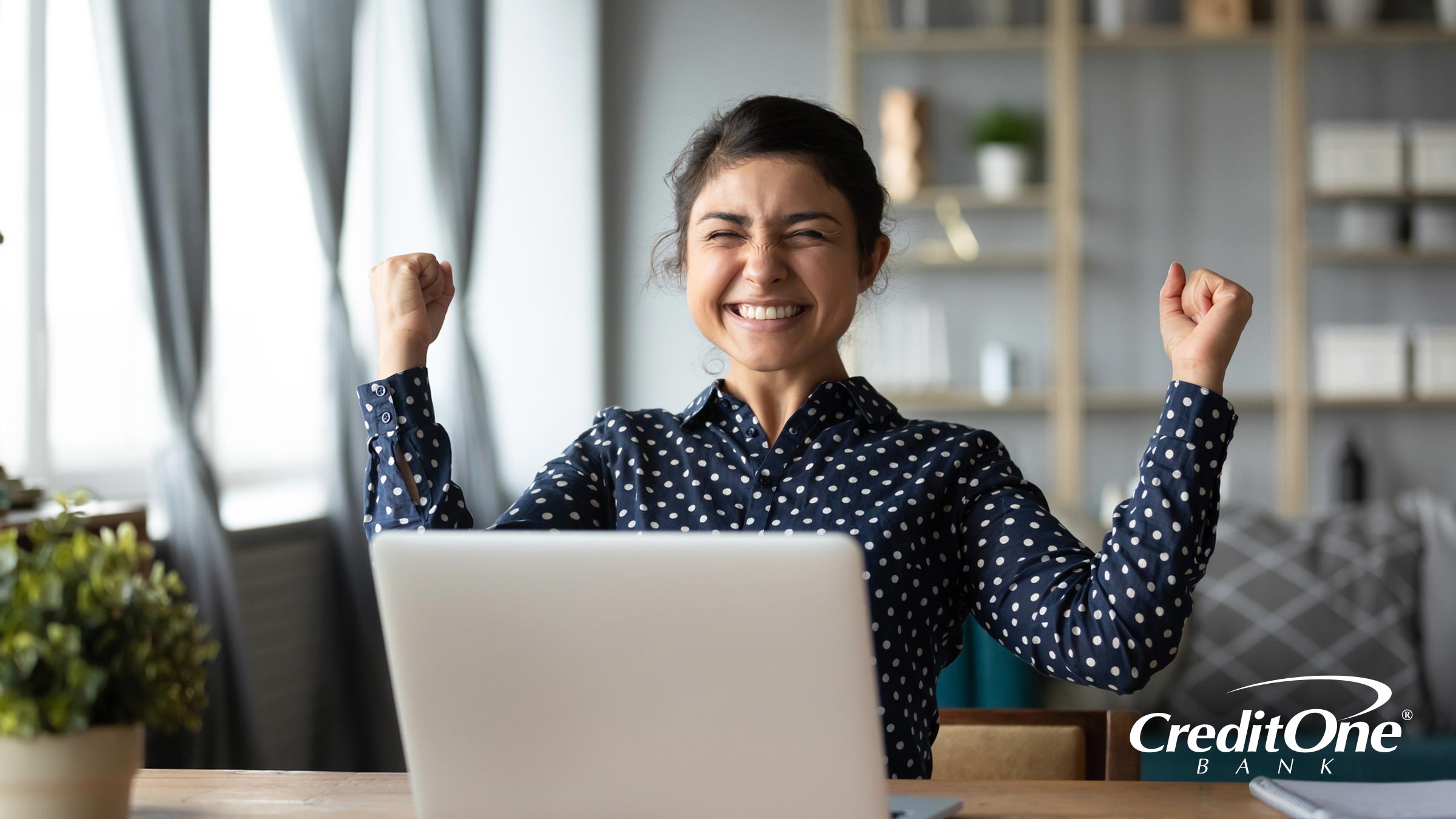A Woman Celebrating With Her Hands in the Air at Her Laptop