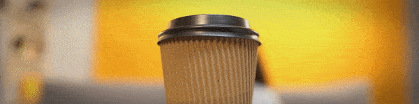 Close-up of a recyclable coffee cup as a young woman grabs with two hands