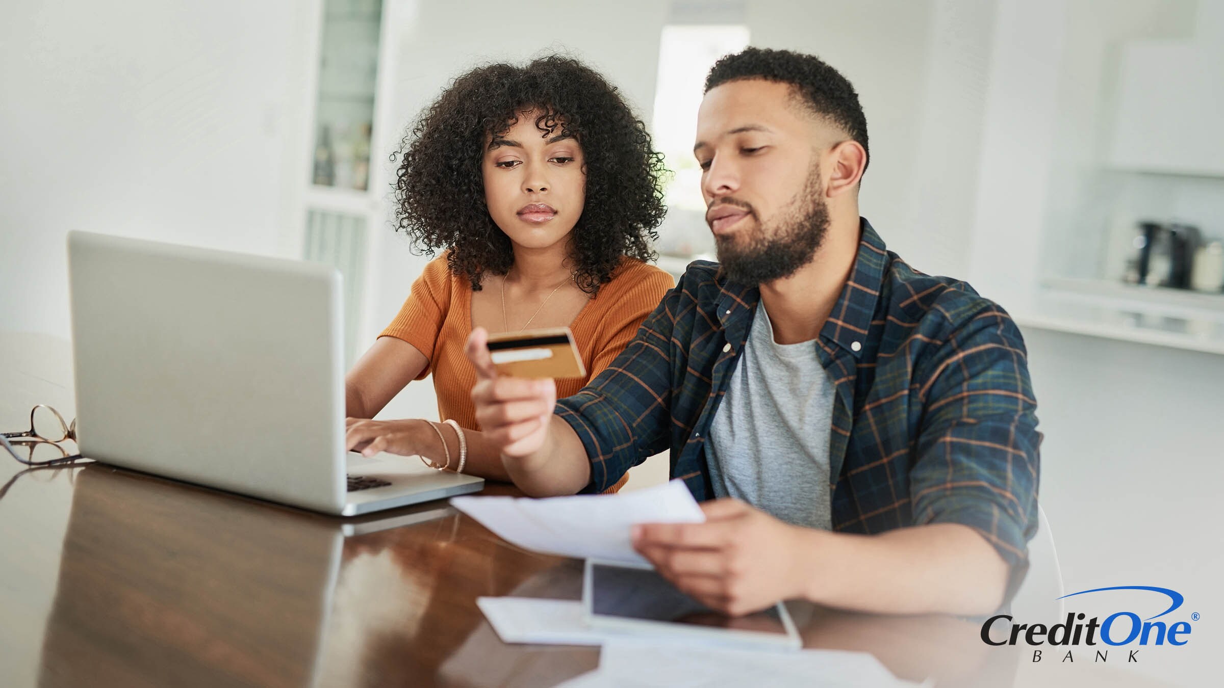 A young couple considers using their credit card to pay bills A young couple considers using their credit card to pay bills