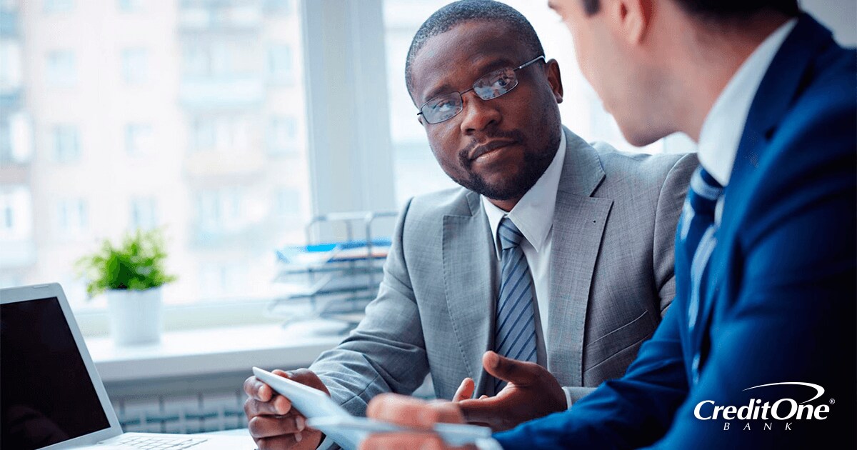 Two businessmen in office reviewing credit scores and other financial statements Two businessmen in office reviewing credit scores and other financial statements