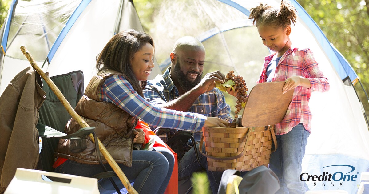 Family of three camping on summer vacation and picking grapes from basket Family of three camping on summer vacation and picking grapes from basket