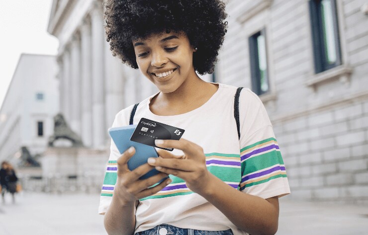 A young woman holding her mobile phone and credit card and smiling