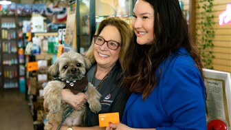 Las Vegas Blogger, right, poses for a photo with a customer at The Wagging Tail while holding the Best Friends Animal Society co-branded Credit One Bank credit card.