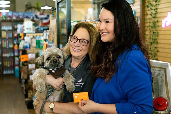 Las Vegas Blogger, right, poses for a photo with a customer at The Wagging Tail while holding the Best Friends Animal Society co-branded Credit One Bank credit card.